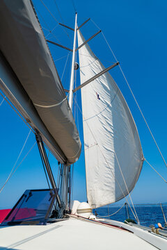 Mainsail on a sailing yacht while cruising across the sea under a clear blue sky. Concept of wind power, sailing, navigation, freedom and life aboard.
