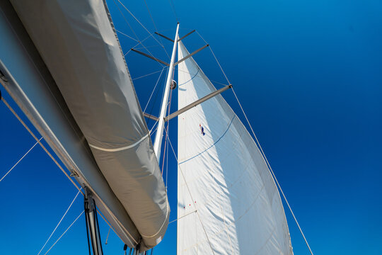 Close up view of the mainsail on a sailing yacht while cruising across the sea under a clear blue sky. Concept of wind power, sailing, navigation, freedom and life aboard.