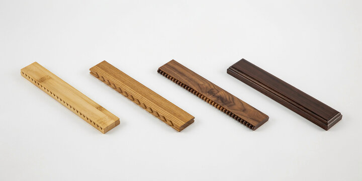 Four long wooden strips with detailed notched edges on a plain white background