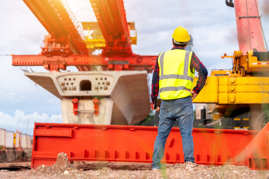 A construction engineer inspecting a large bridge project with launching gantry and crane, representing civil engineering, site supervision, safety and infrastructure development.