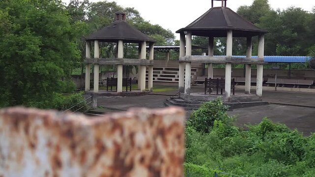 Hexagonal concrete shelters within an elevated ritual platform looking down toward a wide stone staircase, offering an artistic composition that speaks to cultural continuity and silent transitions.