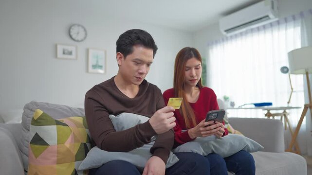 Asian couple using smartphone shopping online in living room at home. 