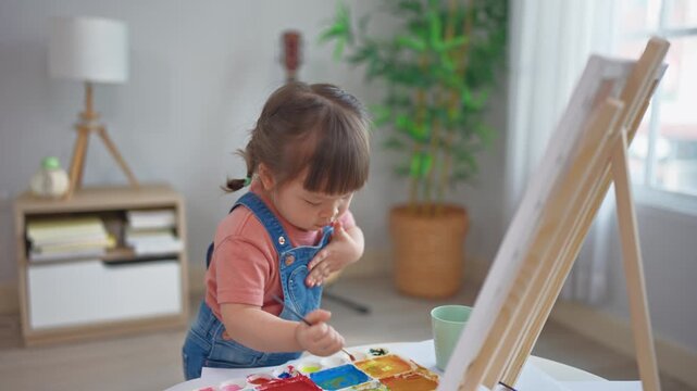 Asian young baby girl enjoy painting on a board in living room at home.