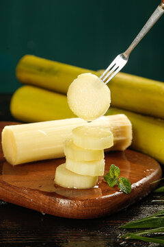 Fresh Yellow Sugarcane Stalks Sliced on Wooden Board with Fork Detail Display