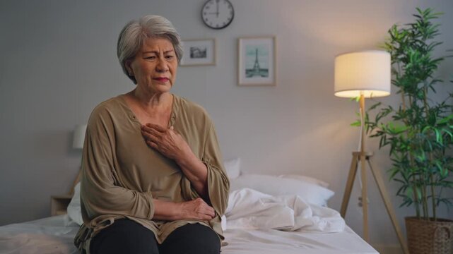 Asian senior elderly depressed woman sitting alone in bedroom at home. 