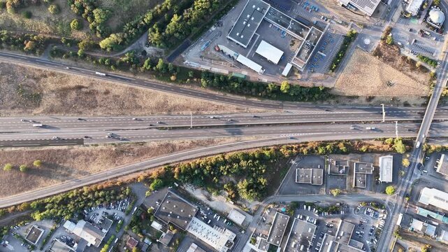 Aerial view of a multi-lane highway intersection surrounded by industrial buildings and greenery in Sausheim, Grand Est, France.