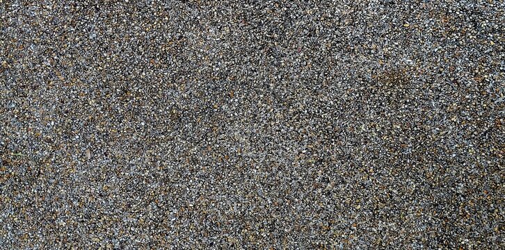 Close-up texture background of exposed aggregate concrete floor with fine gravel pebbles in top view.