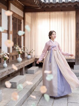 Young woman in hanbok stands serenely in a traditional Korean courtyard setting