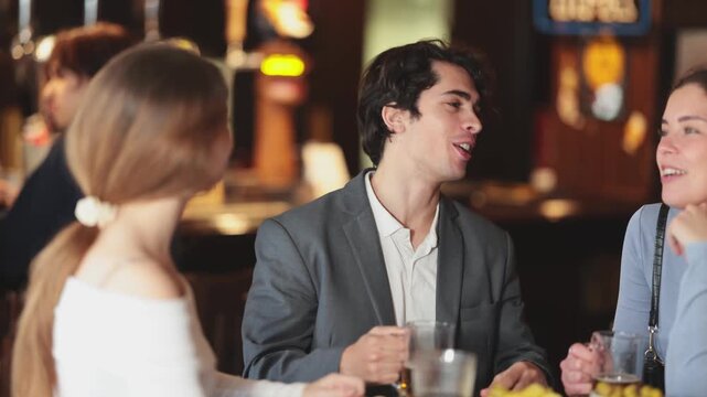 Group of friends spending time in bar, having fun while drinking beer and talking