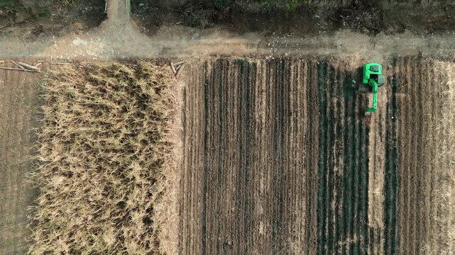 Drone footage showing an aerial view of agricultural fields, including harvested sugarcane and pomelo orange orchards, with heavy machinery parked near a rural road.