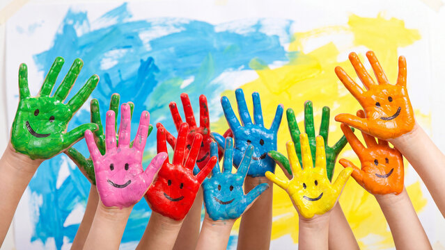 Children's painted palms with smile drawings are displayed together in a close group shot symbolizing friendship, teamwork, and artistic fun.