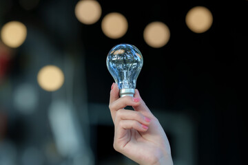 Professional woman holding a clear light bulb, symbolizing ideas, innovation, creativity, inspiration, business solutions, and new opportunities in a modern professional setting. © Kieng