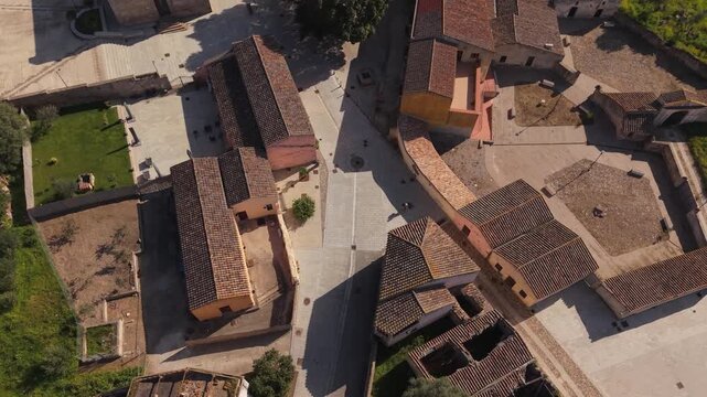 Person Walking Through Ghost Town In Tratalias Vecchia Village In Province of Sulcis Iglesiente, Italy. - aerial shot