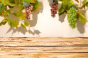 Wooden table with blurred grape bunches and vine leaves as autumn harvest mockup background © Svetlana Kolpakova