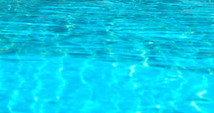 clear blue swimming pool water with shimmering reflections and tiled pattern, gentle moving ripples, abstract summer background ideal for travel, leisure, relaxation, wellness, refreshing, luxury pool