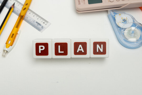 Business organization and administration concept featuring letter blocks spelling &ldquo;PLAN&rdquo; on a clean office desk, surrounded by office stationaries.