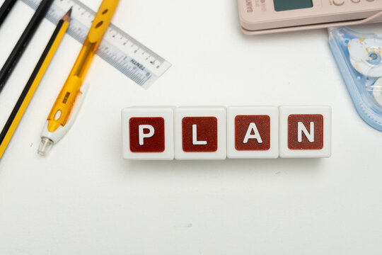 Business organization and administration concept featuring letter blocks spelling &ldquo;PLAN&rdquo; on a clean office desk, surrounded by office stationaries. Symbolizing corporate mission, strategic planning, b
