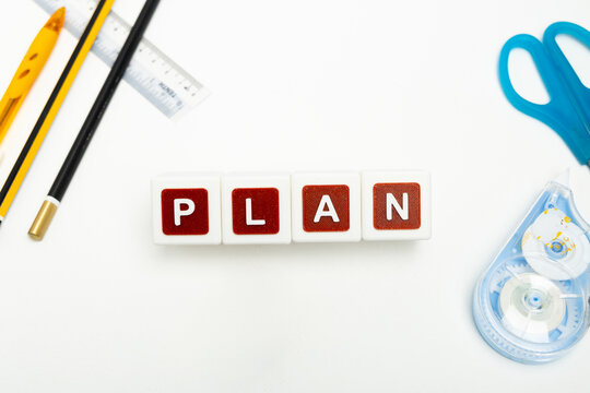 Business organization and administration concept featuring letter blocks spelling &ldquo;PLAN&rdquo; on a clean office desk, surrounded by office stationaries.