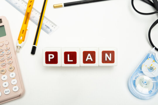 Business organization and administration concept featuring letter blocks spelling &ldquo;PLAN&rdquo; on a clean office desk, surrounded by office stationaries. Symbolizing corporate mission, strategic planning, b