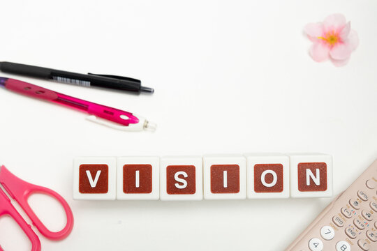 Business organization and administration concept featuring letter blocks spelling &ldquo;VISION&rdquo; on a clean office desk, surrounded by office stationaries.