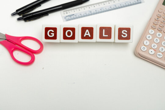 Business organization and administration concept featuring letter blocks spelling &ldquo;GOALS&rdquo; on a clean office desk, surrounded by office stationaries.