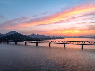 Obraz premium Bridge spanning river with sunset sky and distant mountains