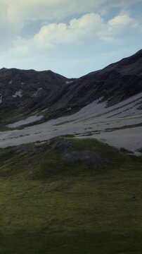 Frozen peaks tower over a tranquil valley, where gentle mists curl around lush greenery. Morning light casts a warm glow across the serene landscape, creating a peaceful atmosphere.