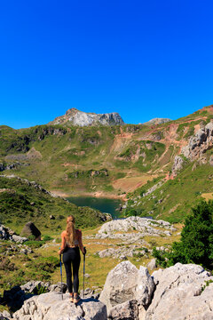 woman hiker standing on rock enjoying view of mountain lake in somiedo asturias spain