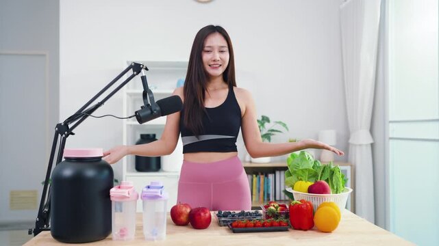 Asian fitness influencer recording healthy nutrition vlog with smartphone camera. Young female content creator talking about diet, fresh organic food and wellness lifestyle.