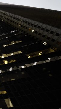 Tall buildings rise sharply against the dimming sky. Lights flicker on, creating a fascinating interplay of shadows and illumination. The scene captures the essence of urban life.