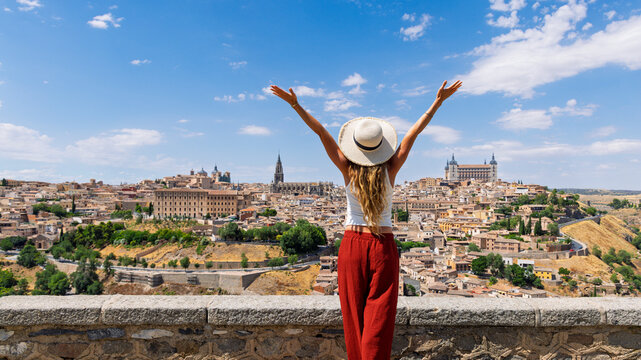 woman with arms raised open looking at toledo panoramic cityscape in spain