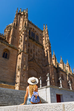 woman sitting on steps looking at facade of salamanca cathedral in spain