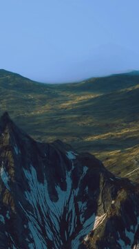 Majestic mountains rise high into the sky, their rocky peaks adorned with patches of snow. Soft shadows stretch across the green valleys as twilight settles in, creating a peaceful atmosphere.