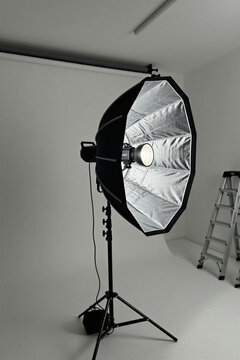 Pro photo studio setup with parabolic softbox light modifier and strobe flash. Equipment for creating clean minimalist commercial video and photo production.