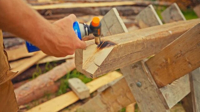 Person Uses Portable Gas Blowtorch To Char The Exposed Beveled End-Grain Of An Upright Wooden Post. Close-up Shot