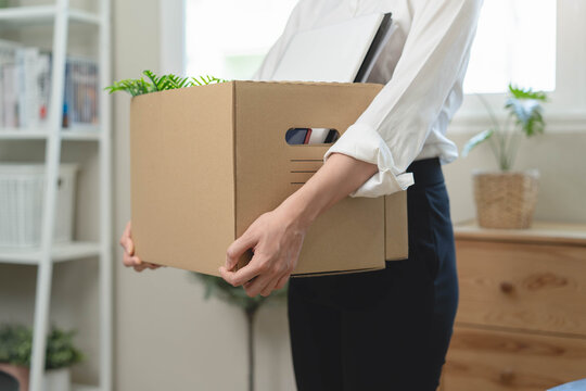 Close-up of businesswoman holding a cardboard box with personal belongings after resignation or being laid off from her job.