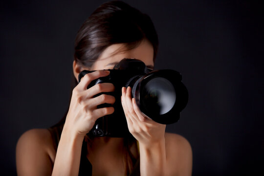 Woman photographer taking photograph against black background 
