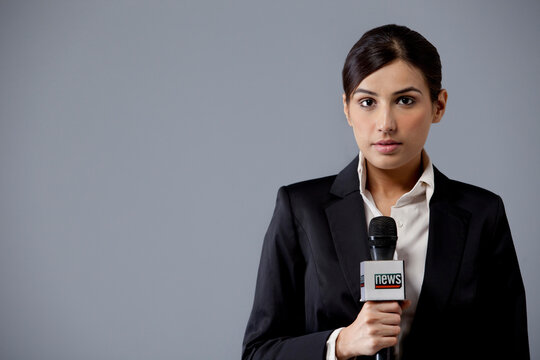 Portrait of young female newscaster against colored background 