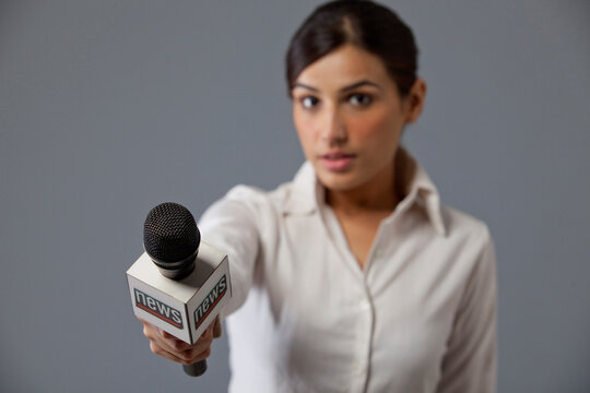 Close-up of young woman news reporter holding out microphone 