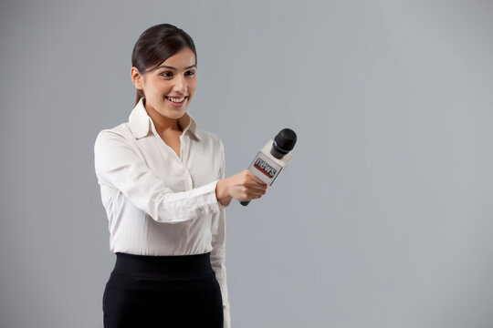 Portrait of smiling reporter holding out microphone 