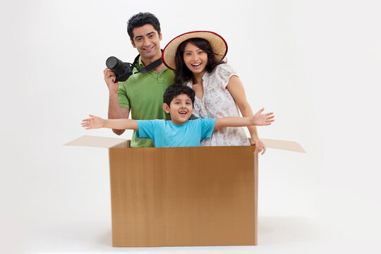 Happy family on vacation having fun while sitting in cardboard box 