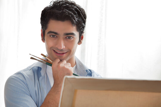 Close-up of handsome young artist painting in art studio 