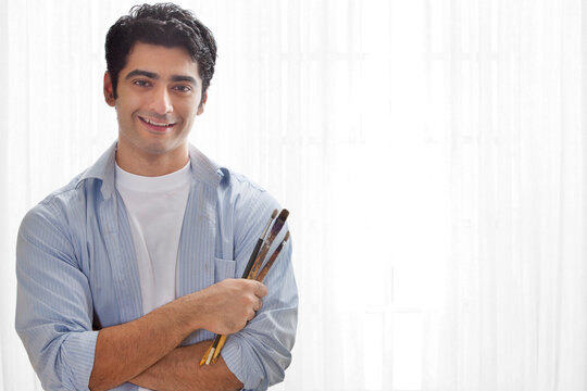 Smiling male painter holding paintbrush 
