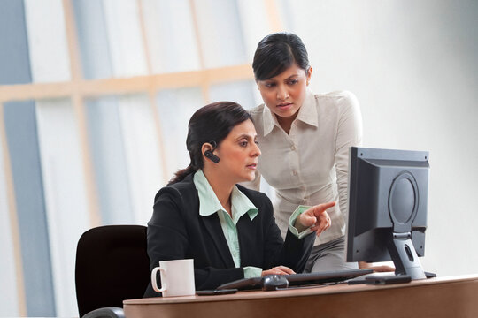 Female executives discussing while looking at computer 