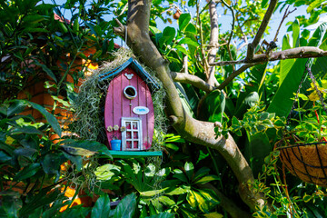 Naklejka premium Whimsical pink birdhouse hanging in a lush garden