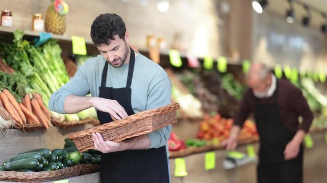 Man seller working in supermarket and lays out fresh zucchini on counter. High quality 4k footage