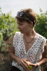 Naklejka premium Thoughtful woman holding a ripe peach in a garden