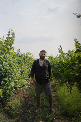 Naklejka premium Smiling tattooed man standing in a vineyard
