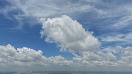 Puffy white cumulus clouds drift across a blue sky © Cavan