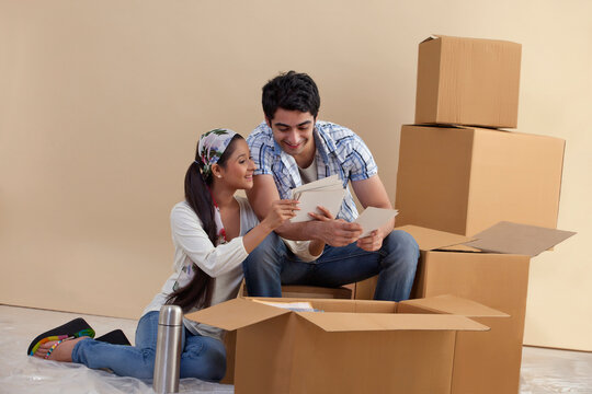 Young couple looking at photographs together at home 